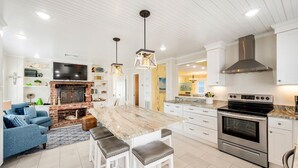 Una cocina moderna con una isla central, horno empotrado y chimenea.
