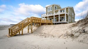 Una propiedad frente a la playa con una escalera de madera que da a un balcón.