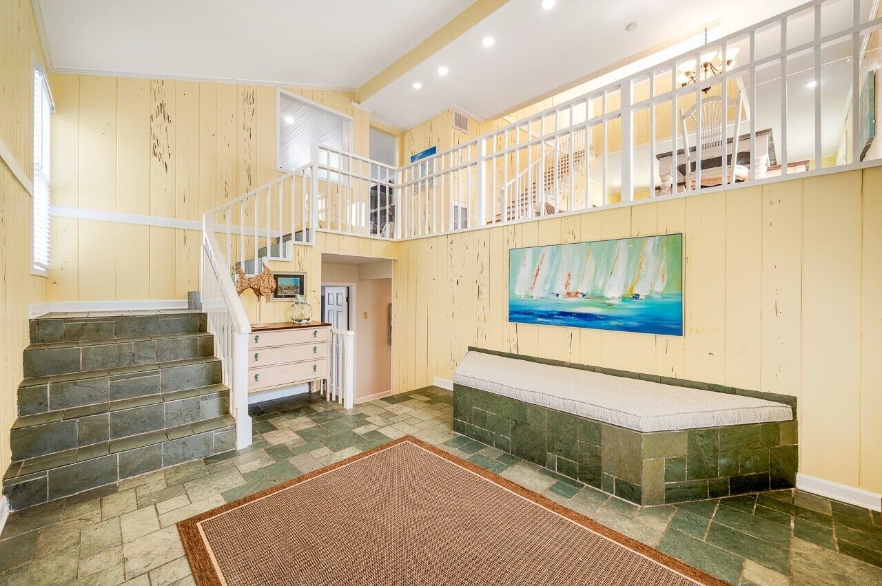 Um espaço amplo com escada, um banco e uma pintura na parede.
