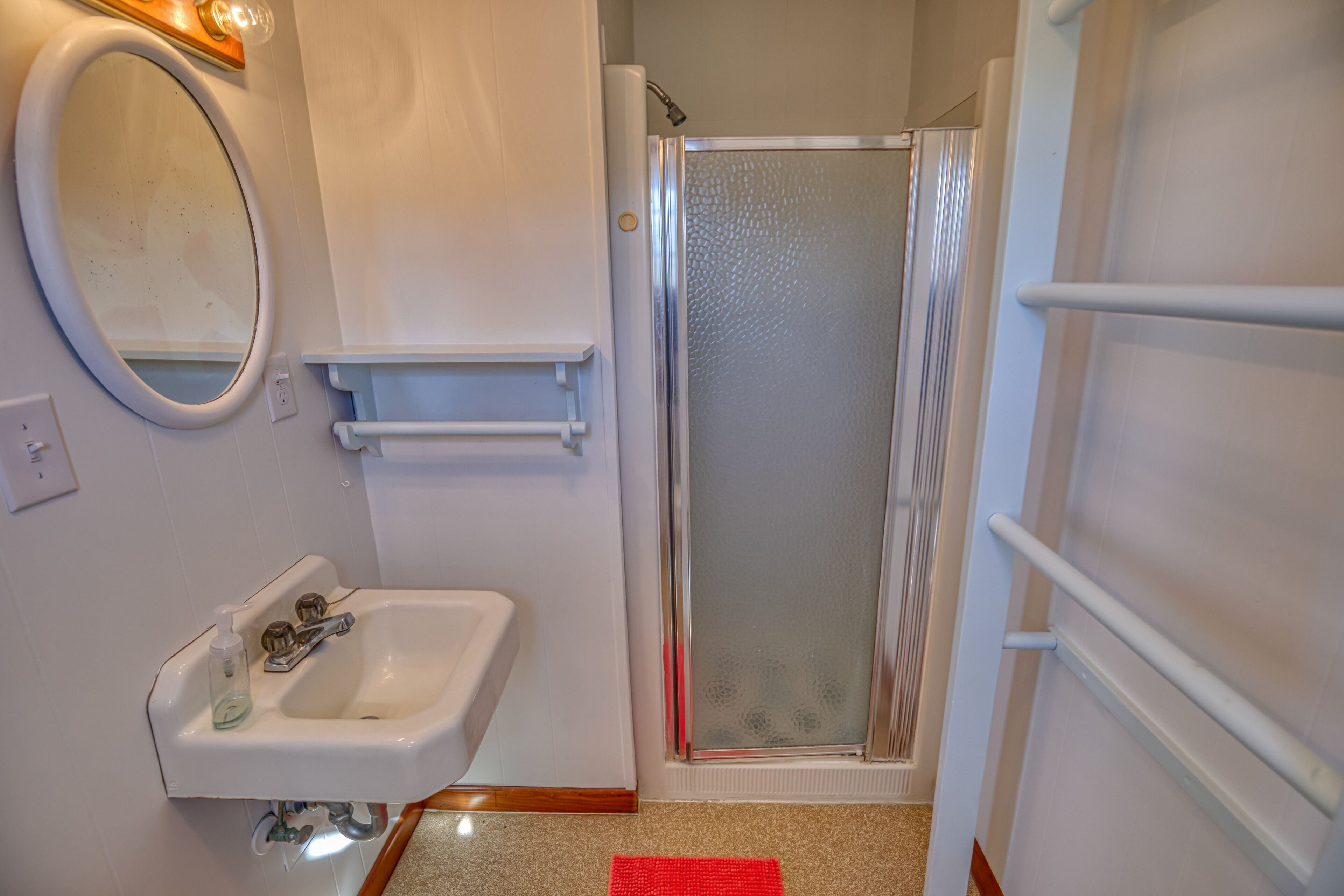 Une salle de bain équipée d’un lavabo, d’un miroir et d’une douche à parois de verre.