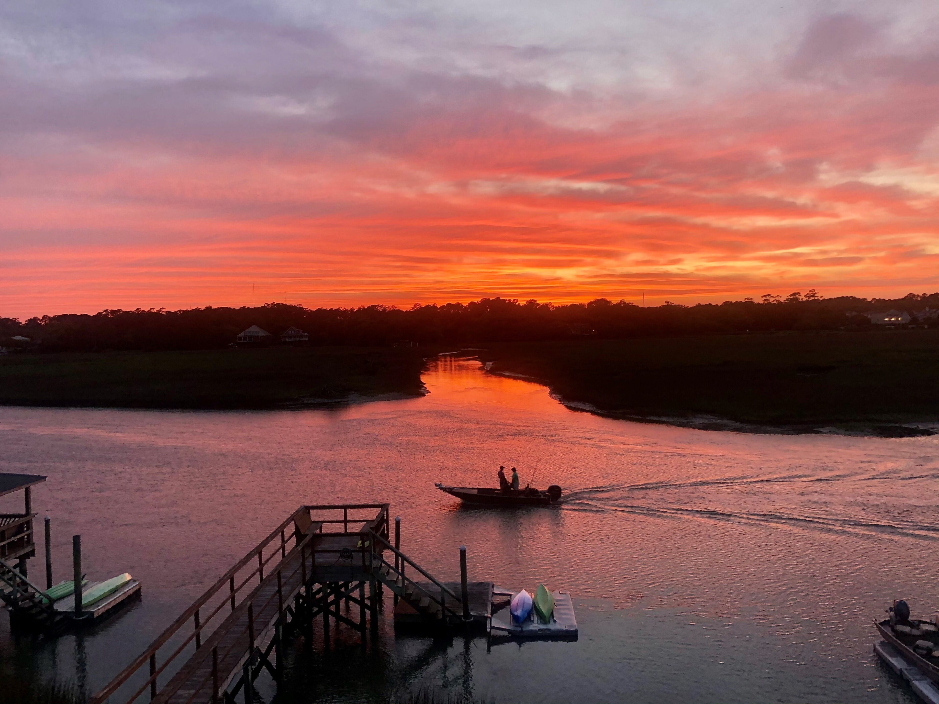 Un atardecer sobre un río con un muelle y barcos.