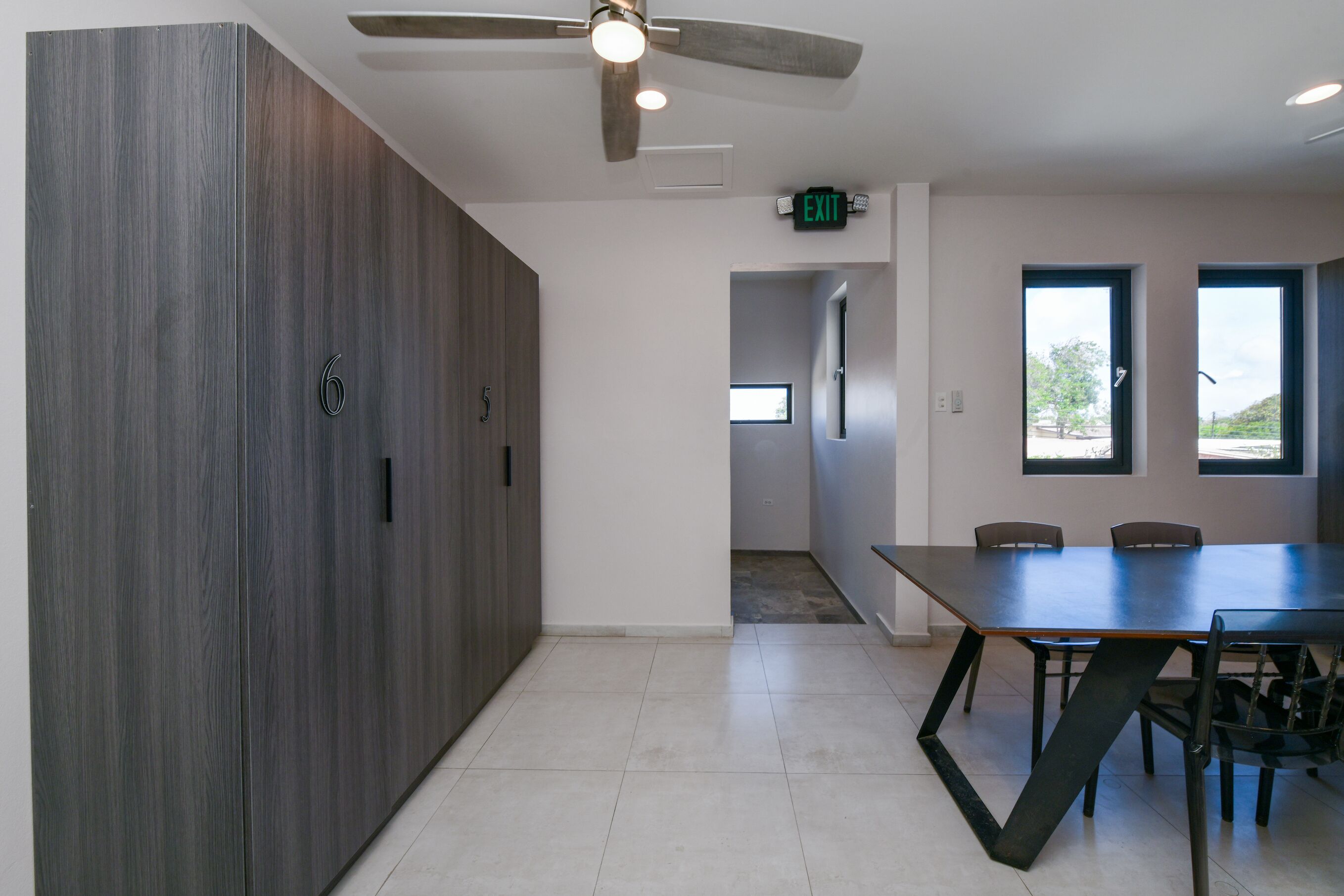 Une salle de conférence avec une grande table, des chaises, un ventilateur de plafond et une porte portant l’inscription « SORTIE ».