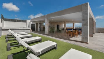 Una terrazza sul tetto con lettini, un'area pranzo e vista sulla città.