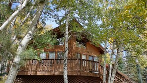 A wooden cabin with a balcony, surrounded by trees and a wooden deck. - Mountain Chalet Tucked in Aspen Grove with Mountain Views (Angel Fire)