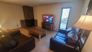 Una sala de estar moderna con chimenea, televisor y un ventanal grande.
