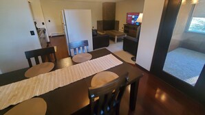 Comedor con mesa de madera, sillas, un mantel tejido y una lámpara en el techo.
