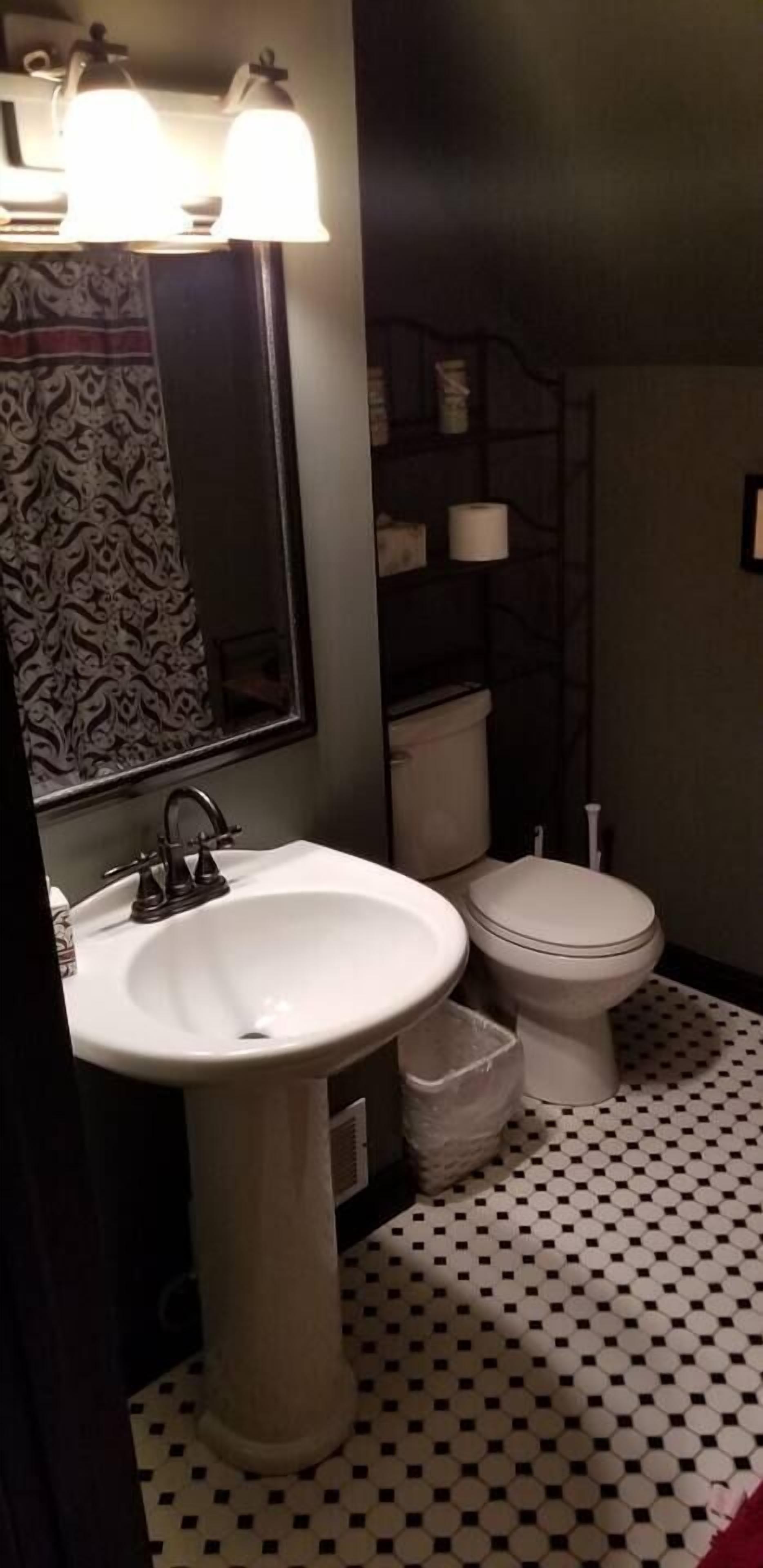 A bathroom with a white sink, a toilet, and a mirror. There are two wall-mounted lights above the sink.