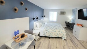 Un dormitorio moderno con cama, mesitas de noche, un escritorio y televisión.