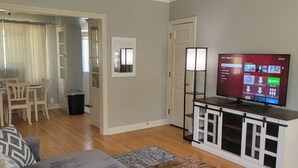 A living room with a gray sofa, a wooden coffee table, a TV on a white cabinet, and a ceiling fan. - Historic McKennan Park Apt 3 (1 bed 1 bath) - KP220APT3 (Sioux Falls)