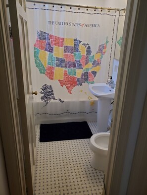 A bathroom with a United States map-themed shower curtain, a white sink, and a patterned floor.