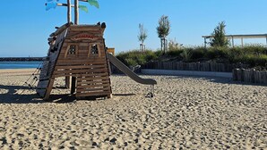 Una torre de salvavidas de madera con un tobogán en una playa arenosa.