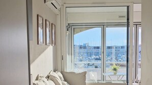Una sala de estar moderna con un sofá, una mesita y vistas a un puerto deportivo.