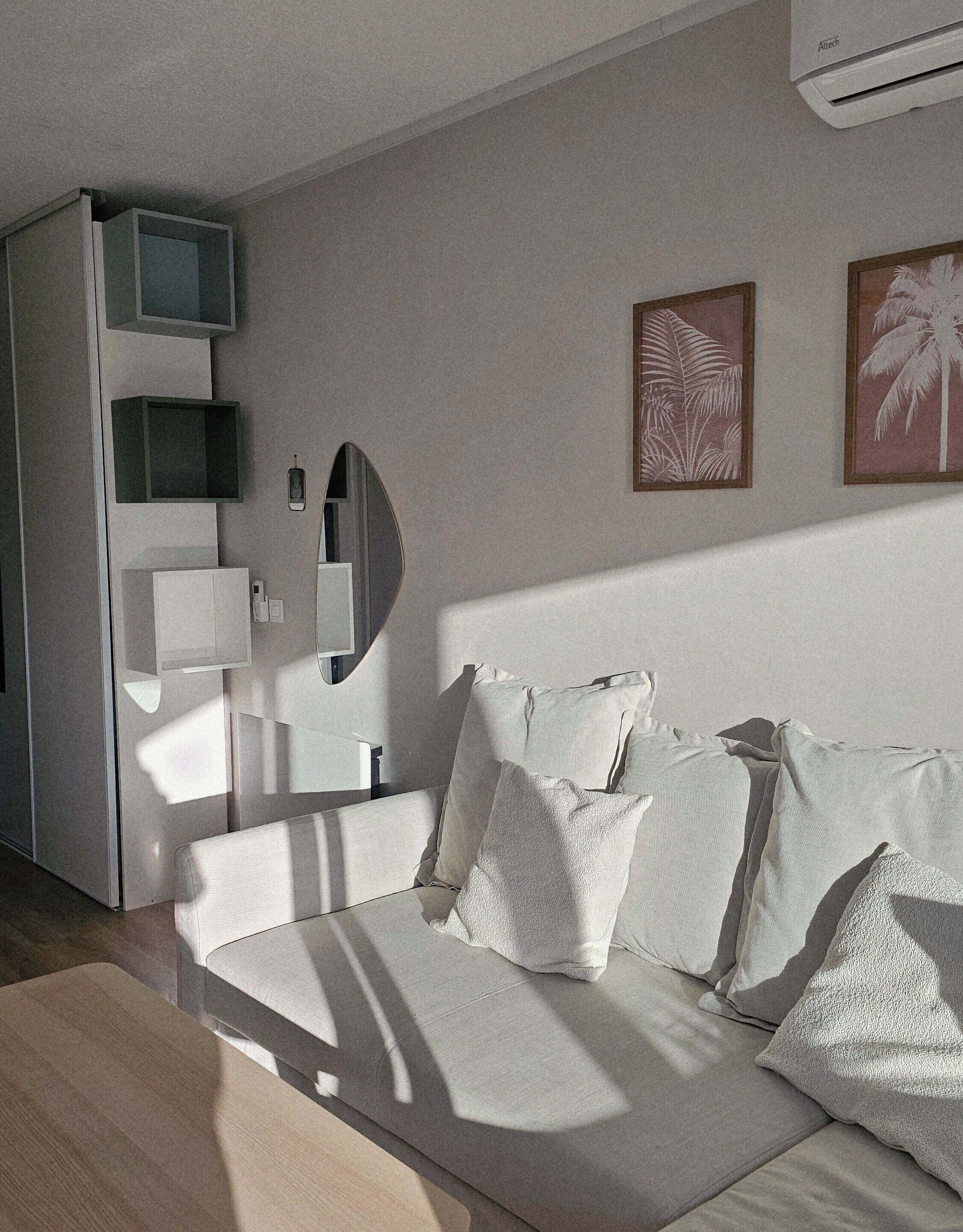 A modern bedroom with a bed, bedside tables, a mirror, and wall-mounted artwork.