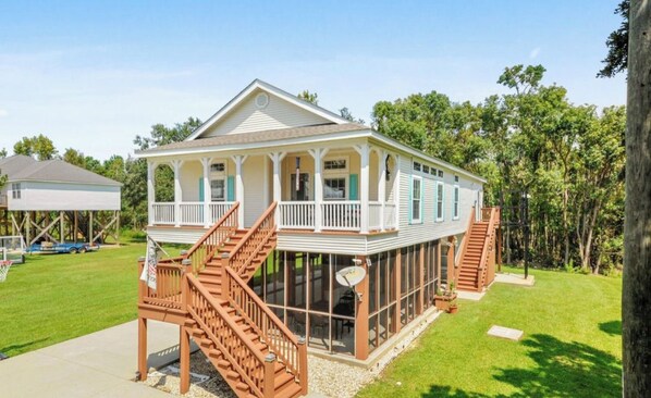 Ein zweistöckiges Haus mit überdachter Veranda und einer Holztreppe.