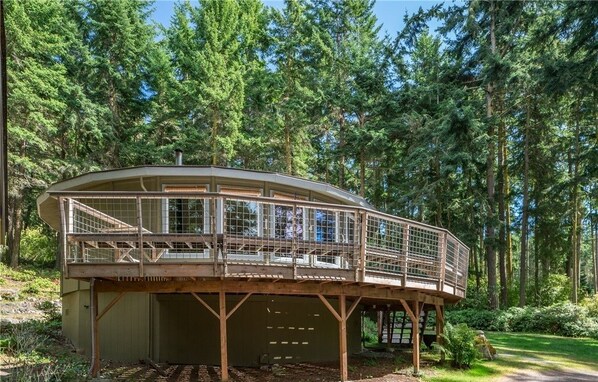 A wooden cabin with a glass enclosure, surrounded by a forest.