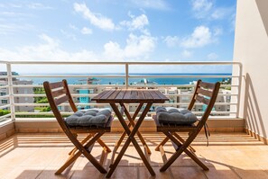 A balcony with a wooden table and two cushioned chairs, overlooking a coastal view with buildings in the background. - Oceanview Lighthouse Villa (Maunabo)