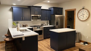 A modern kitchen with dark blue cabinets, stainless steel appliances, and a large island. - Updated Schweitzer condo with beautiful mountain and valley views!  (Sandpoint)