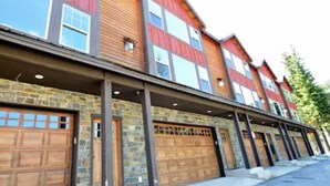 A multi-story building with a stone facade and wooden garage doors. - Updated Schweitzer condo with beautiful mountain and valley views!  (Sandpoint)