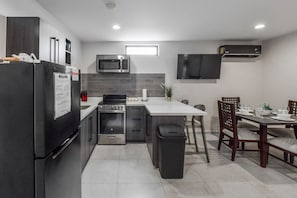 Una cucina moderna con forno integrato, microonde e piano cottura. C'è un'area pranzo con tavolo e sedie.