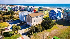 Uma área residencial à beira-mar, com casas coloridas, uma praia e céu claro.