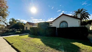 Une maison d’habitation avec une pelouse bien entretenue, un ciel dégagé et un soleil éclatant.