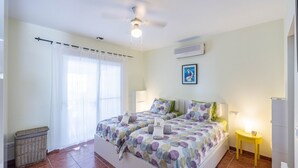 A bedroom with two beds, a ceiling fan, an air conditioner, a small table with a lamp, and a wicker basket. - Villa Flamenca Canillas de Albaida by Ruralidays (Málaga)