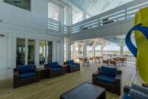 A spacious outdoor deck with wicker furniture, a yellow and blue sculpture, and a view of the water. - Casa Sea-Esta  at Aruba Bay Resort (Corpus Christi)