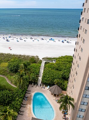 A hotel with a pool, beach, and ocean view.