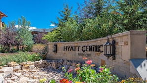 Un mur de pierre sur lequel est inscrit le texte « Hyatt Center Park City » et un jardin aménagé avec différentes variétés de fleurs.