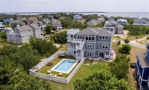 A residential area with houses, a swimming pool, and a view of the ocean.