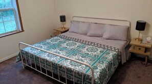 Cozy bedroom with a metal bed frame, patterned bedspread, and two bedside tables with lamps.
