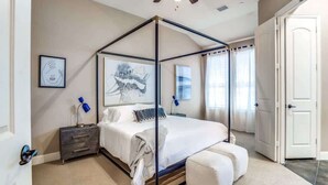 Ein Schlafzimmer mit Himmelbett, Deckenventilator, Nachttisch und einer Tür.