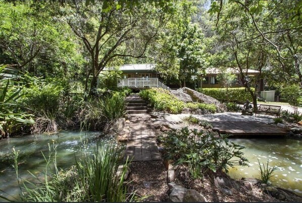 Surrounded by lush greenery and a small body of water, this serene setting offers a tranquil escape.