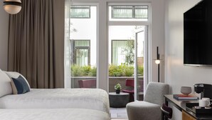 Une chambre d’hôtel avec deux lits, un bureau avec une machine à café, une télévision et une vue sur la verdure environnante.