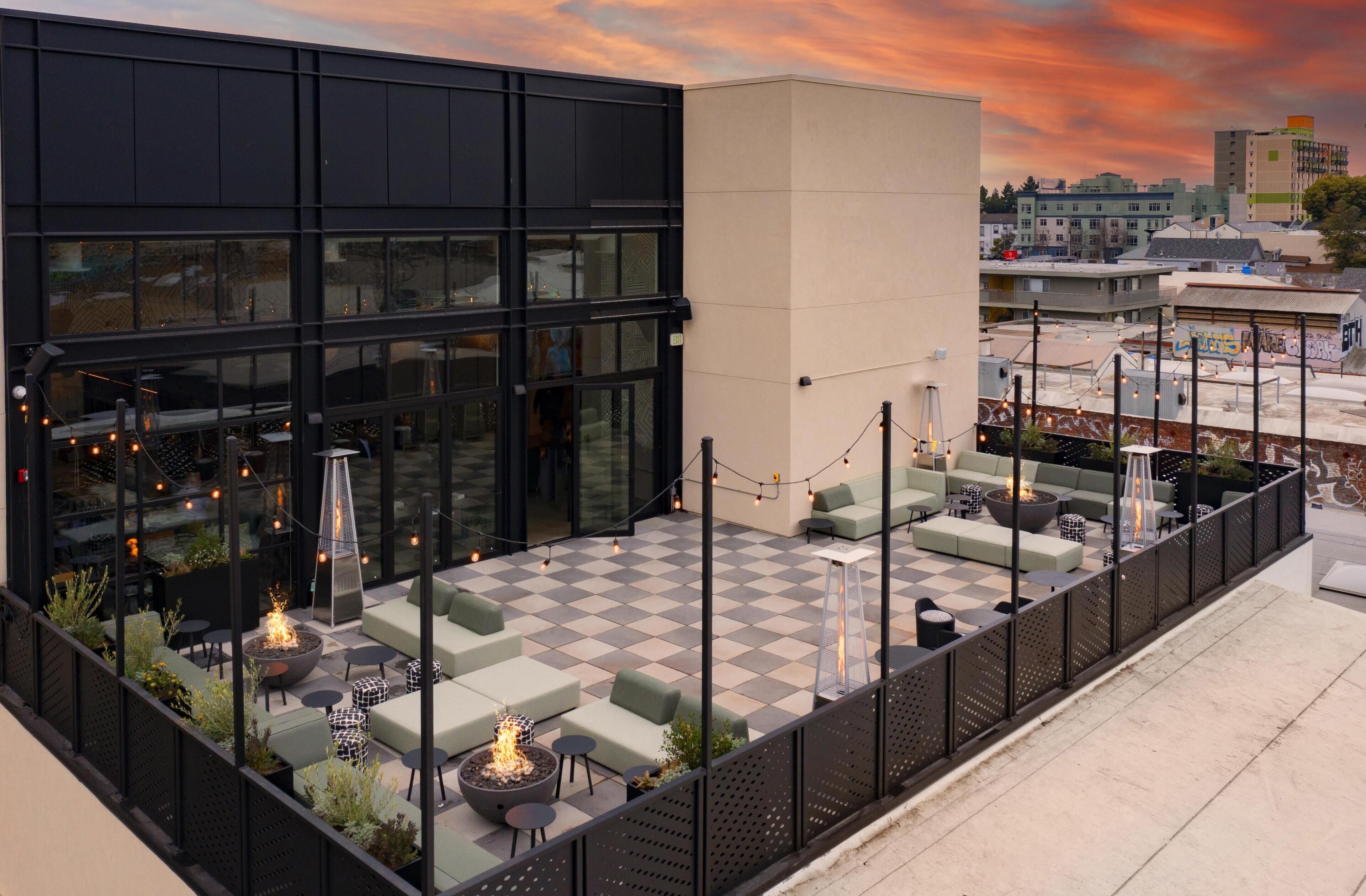A rooftop terrace with outdoor seating, a fire pit, and string lights.