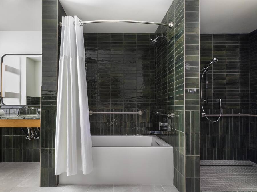 Een moderne badkamer met een bad, douche en een wastafel met spiegel.