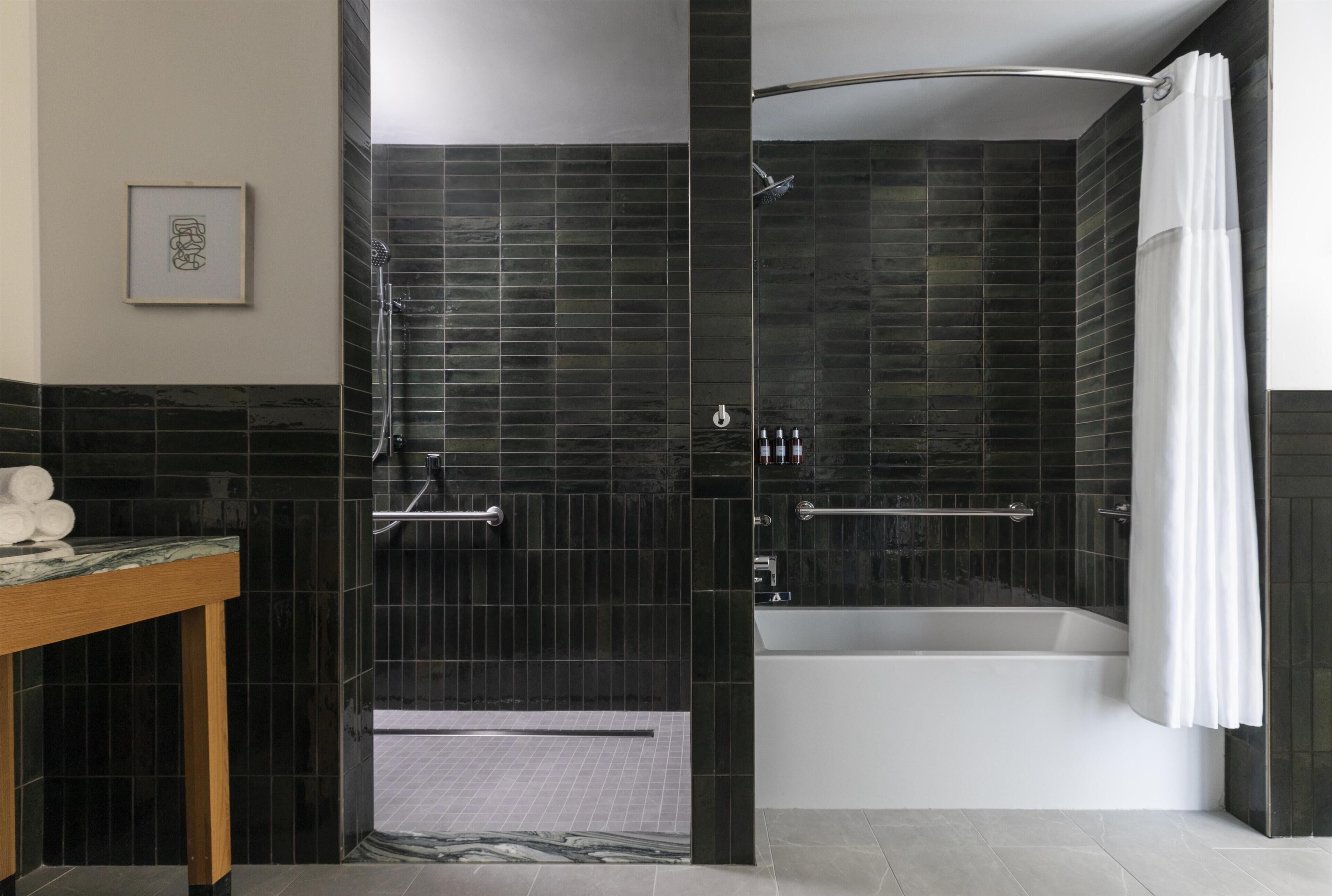 A modern bathroom with a glass-enclosed shower, a bathtub, and a marble countertop.