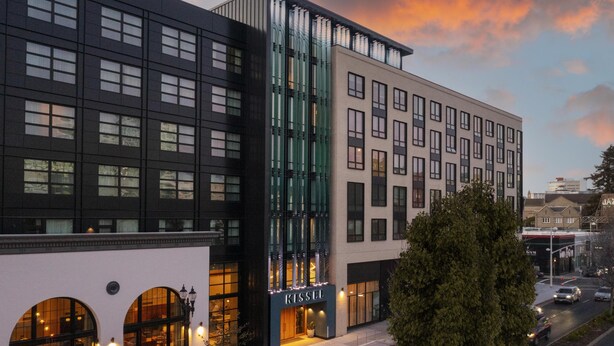 Un hôtel moderne, reconnaissable à son grand panneau « KISSEL », à ses larges fenêtres et à sa vue sur la rue.