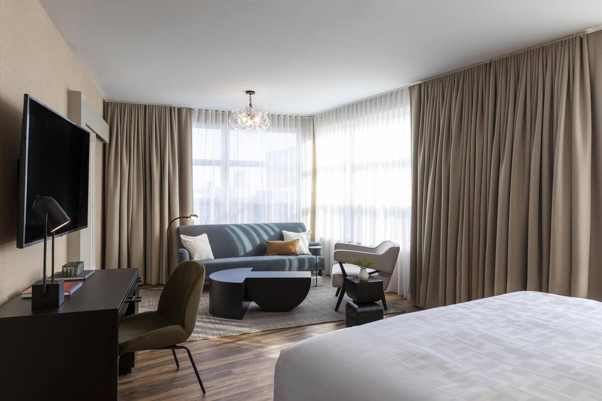 Une chambre d’hôtel moderne équipée d’un lit, d’un canapé, d’un bureau et d’une télévision.