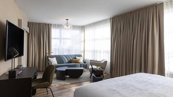 Quarto de hotel moderno com uma cama, um sofá, uma escrivaninha e uma televisão.