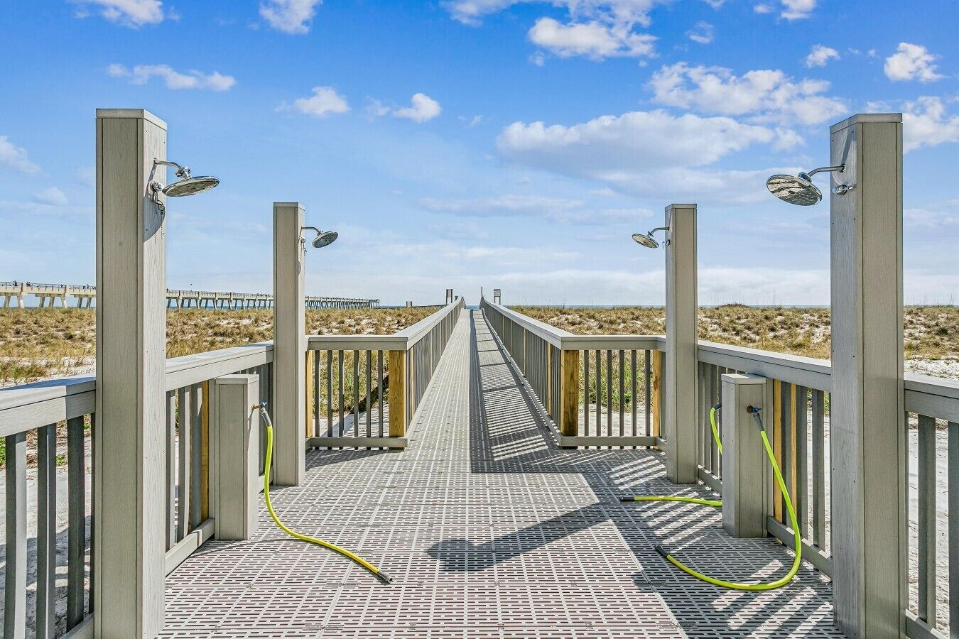 A wooden boardwalk leading to a beach with a clear sky.