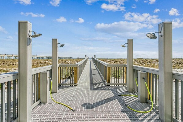 Un paseo marítimo de madera que conduce a una playa con cielo despejado.