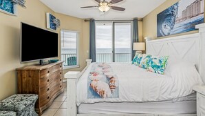 Ein Schlafzimmer mit einem Bett, einem Fernseher, einem Deckenventilator und Kunstwerken an den Wänden.
