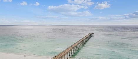 Un muelle largo que se adentra en un mar tranquilo con cielo despejado.