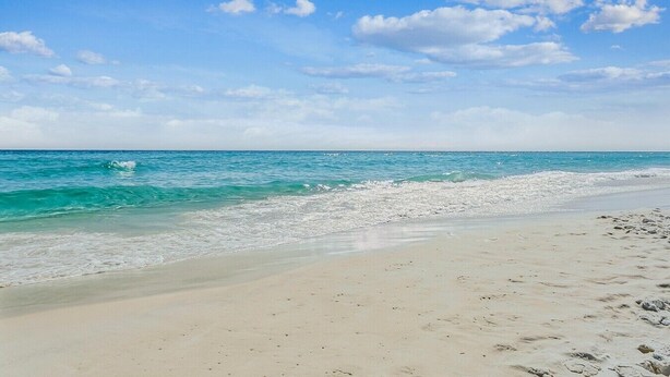 Una playa con agua turquesa cristalina, una orilla de arena y un cielo despejado.