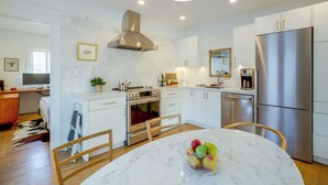 Une cuisine moderne avec des meubles blancs, des appareils en acier inoxydable et un plan de travail en marbre.