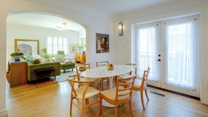 Un salon spacieux comprenant un coin repas, un parquet et de grandes fenêtres.