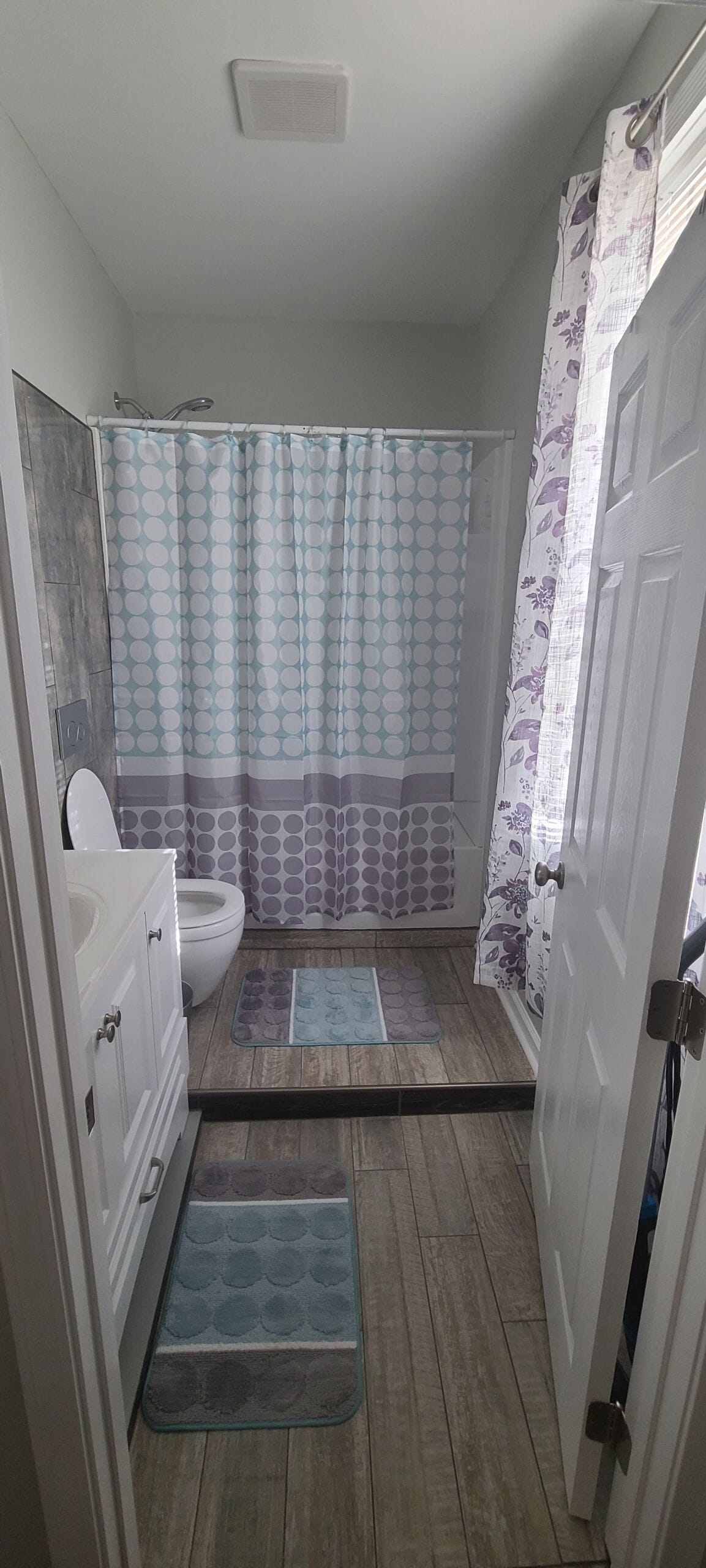 Een badkamer met toilet, wastafel, douchegordijn en een badmat.