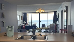 Ett modernt kök med en stor köksö, en inbyggd diskmaskin och utsikt över havet genom stora fönster.