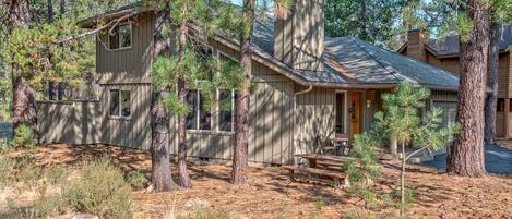 A cabin with a wooden exterior, a chimney, and a small porch with a table and benches.